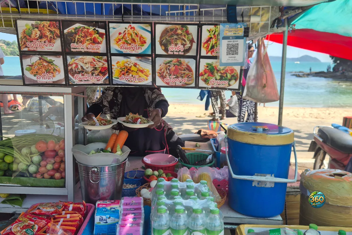 Stand de street food sur Ao Yon Beach à Phuket, avec la plage et la mer visibles en arrière-plan