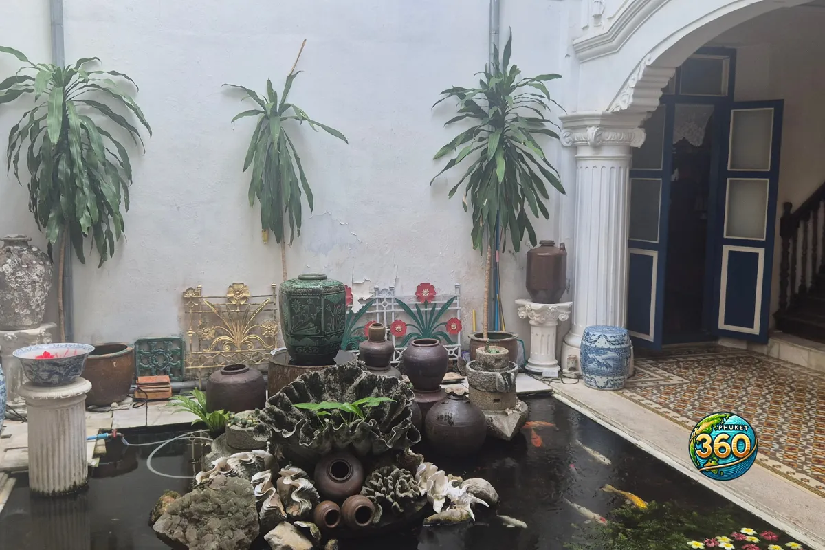 Bassin intérieur de Chinpracha House avec jarres anciennes, plantes et carpes