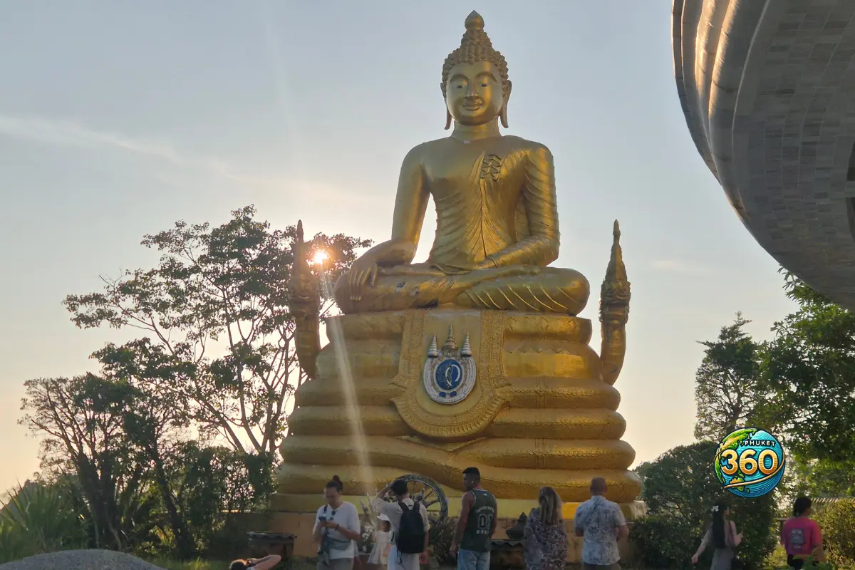 Statue dorée de Bouddha avec des visiteurs au temple du Big Buddha de Phuket au coucher du soleil