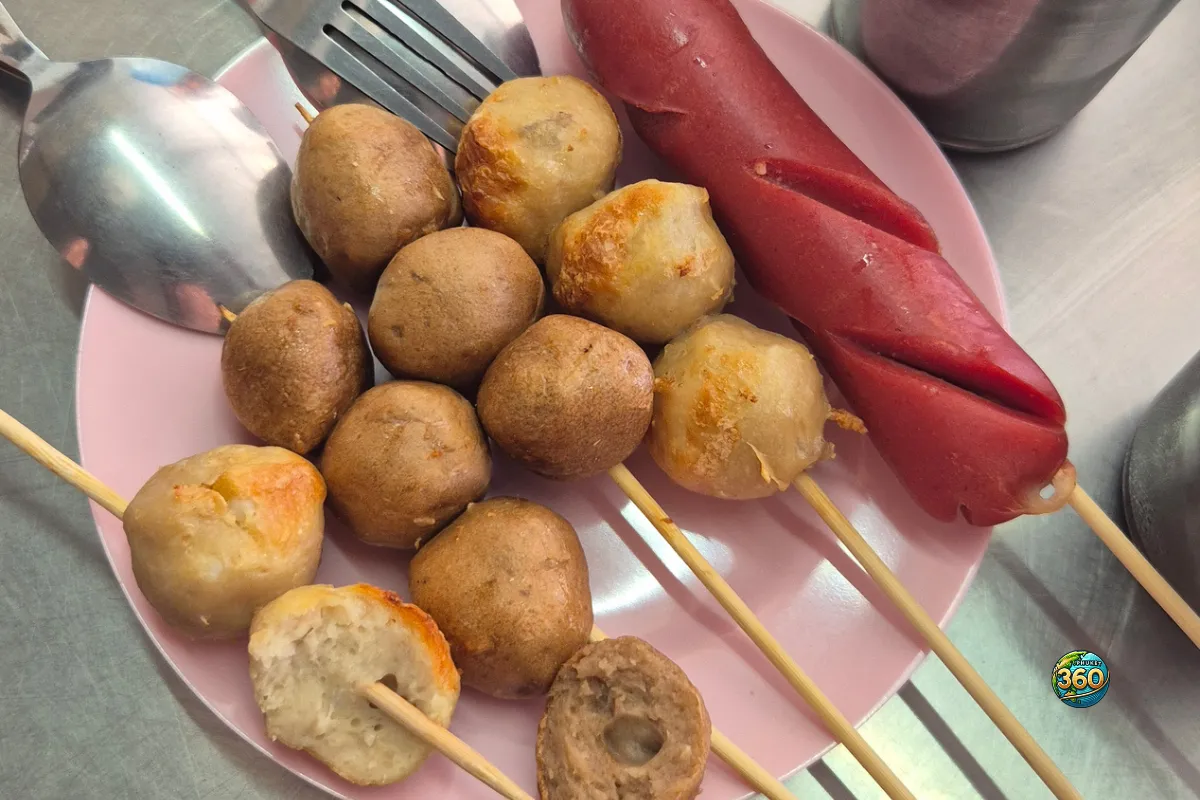 Assiette de brochettes thaïes avec boulettes de viande ou poisson et saucisse rouge servies sur un marché de street food