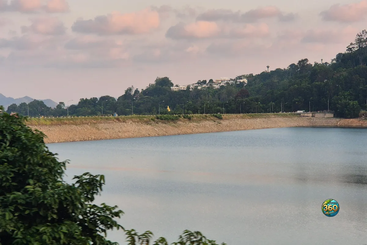 Plan large sur le lac de Chalong Dam Reservoir à Phuket avec rive rocheuse, colline boisée et nuages rosés