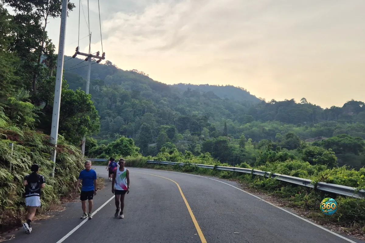 Route courbée près de Chalong Dam Reservoir à Phuket avec promeneurs, coureurs et collines verdoyantes en arrière-plan