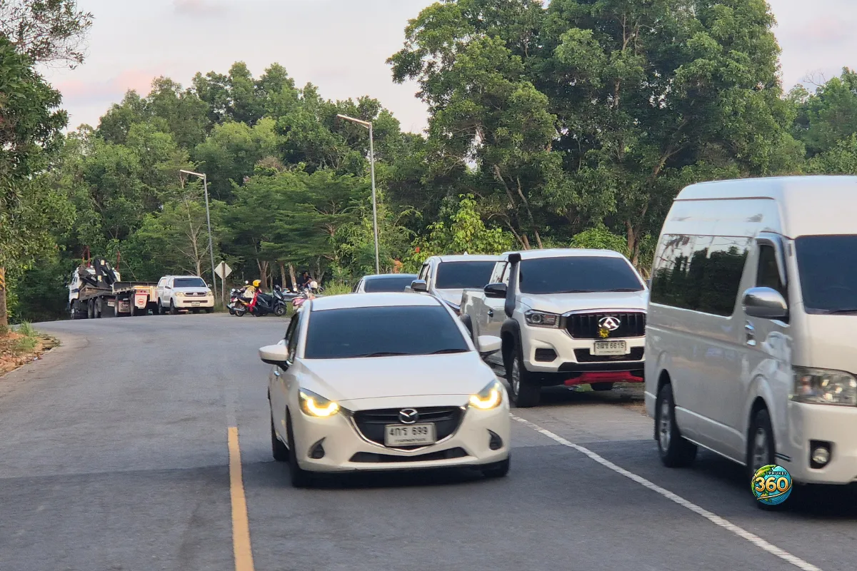 Route près de Chalong Dam Reservoir à Phuket avec voitures, scooters garés et végétation dense autour