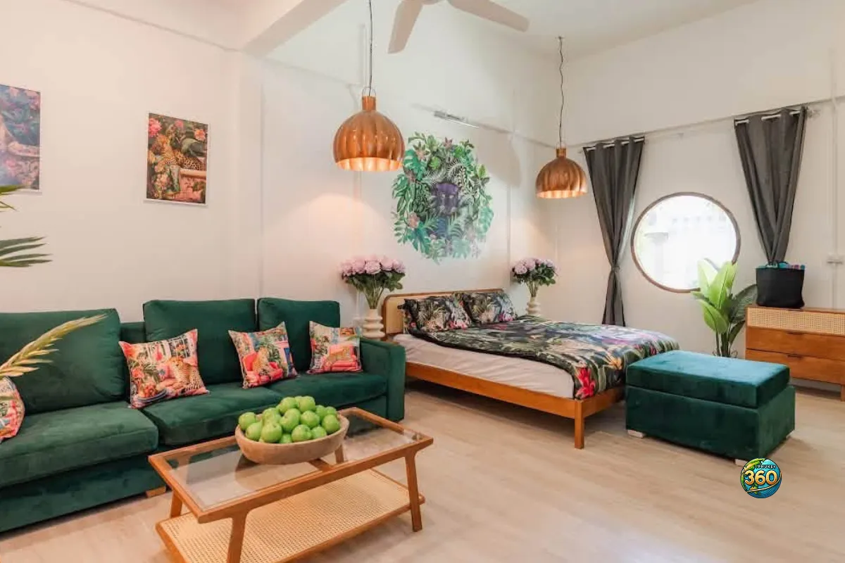 Studio meublé à louer à Phuket avec canapé vert, lit double, table basse, ottoman, climatisation et décoration tropicale