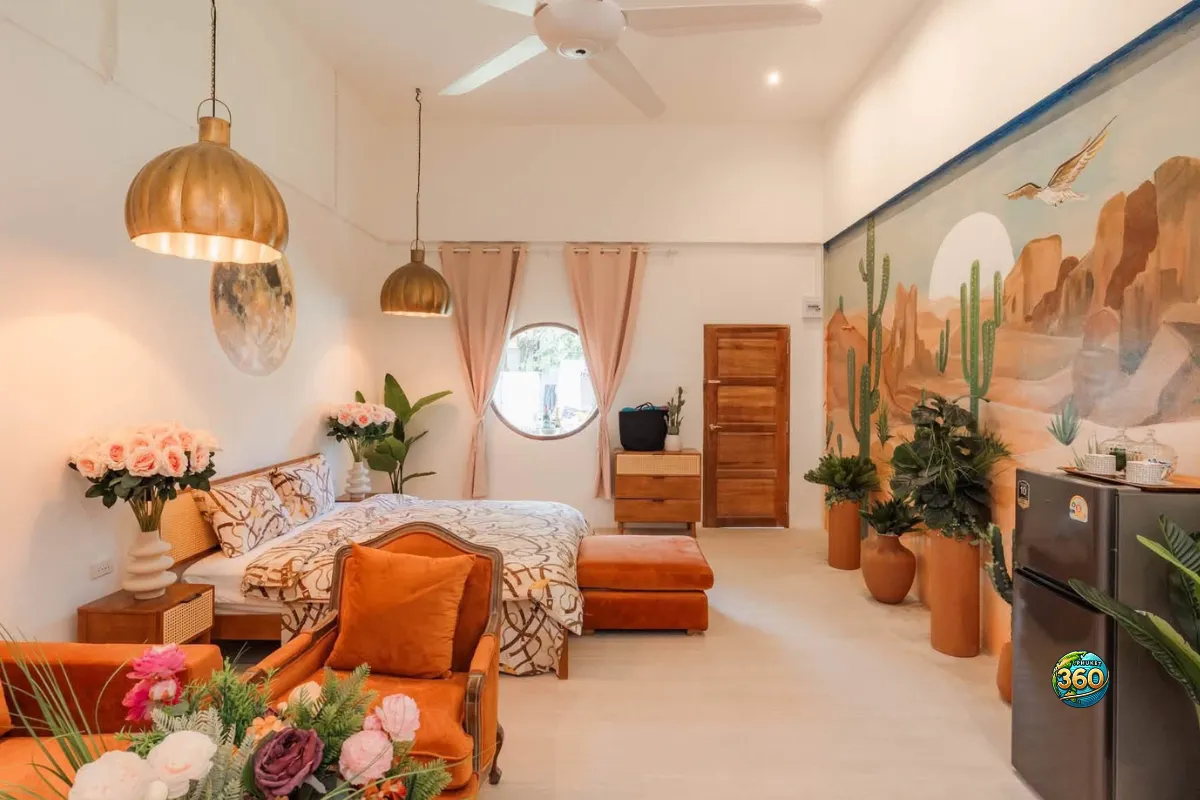 Chambre studio à louer à Phuket avec lit double, fauteuil orange, fresque murale désert, réfrigérateur et décoration chaleureuse