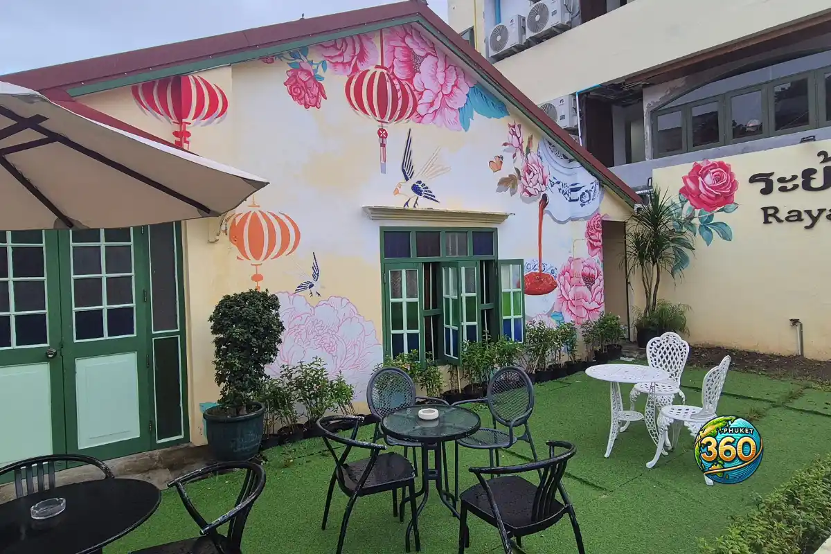 Cour extérieure du restaurant Raya Thai Cuisine à Phuket, avec fresque florale et tables en terrasse