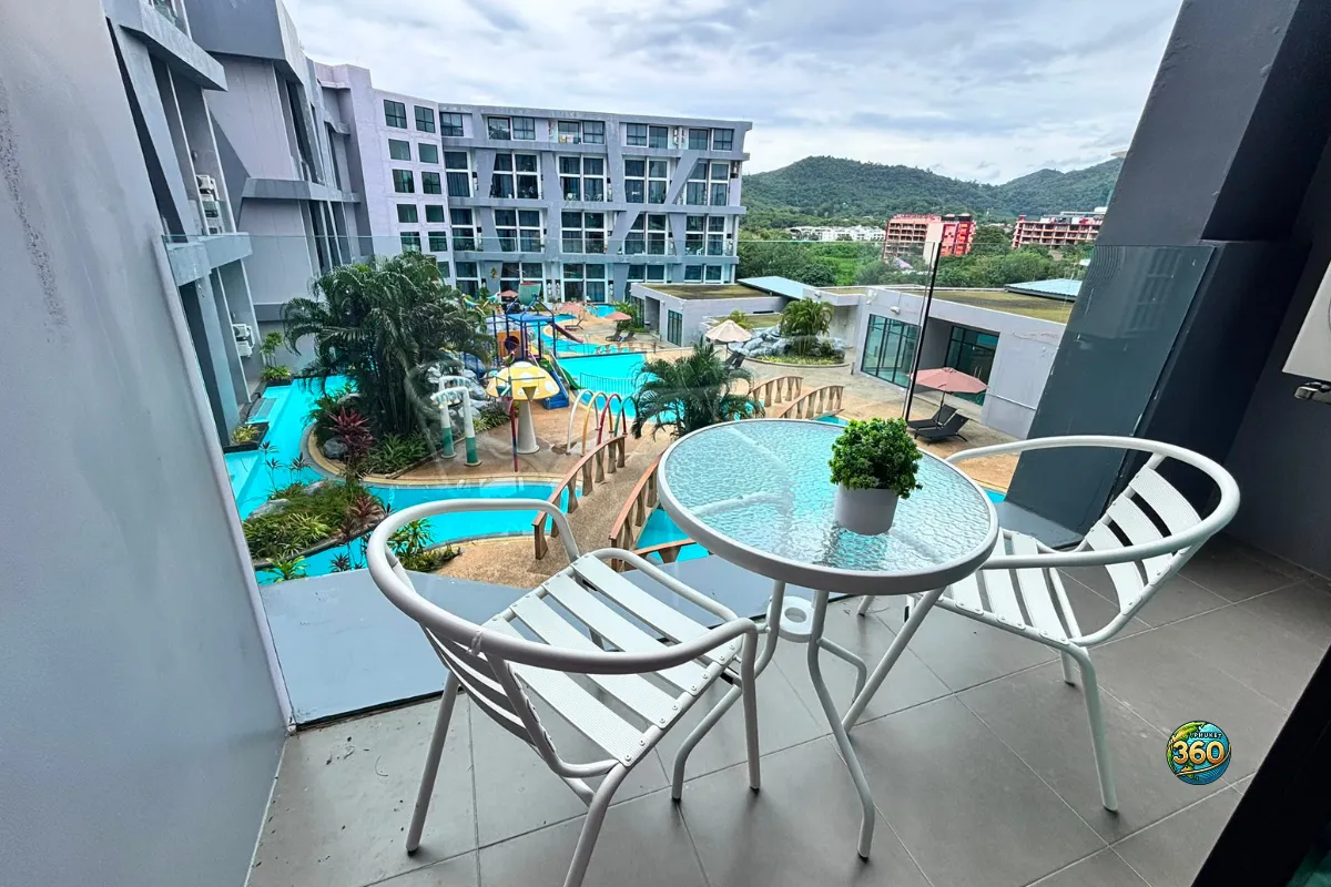 Balcon du duplex à Utopia Nai Harn, Phuket, avec table extérieure, deux chaises et vue sur la piscine de la résidence