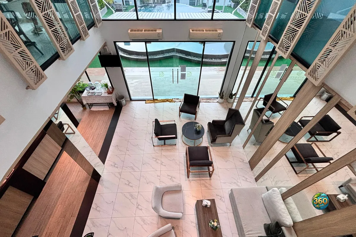 Hall d’accueil de la résidence Utopia Nai Harn à Phuket avec fauteuils, grandes baies vitrées, sol clair et vue vers l’extérieur