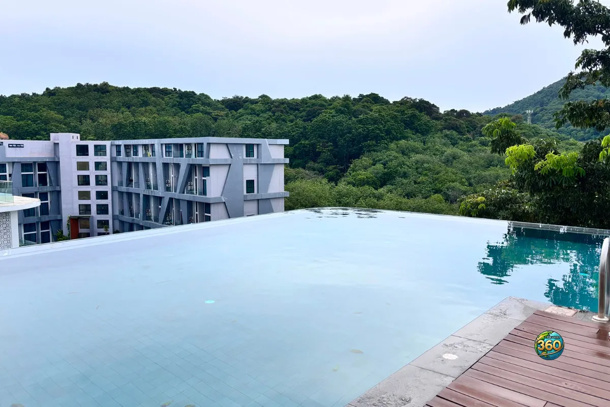 Piscine à débordement de la résidence Utopia Nai Harn à Phuket avec vue sur les bâtiments et les collines verdoyantes