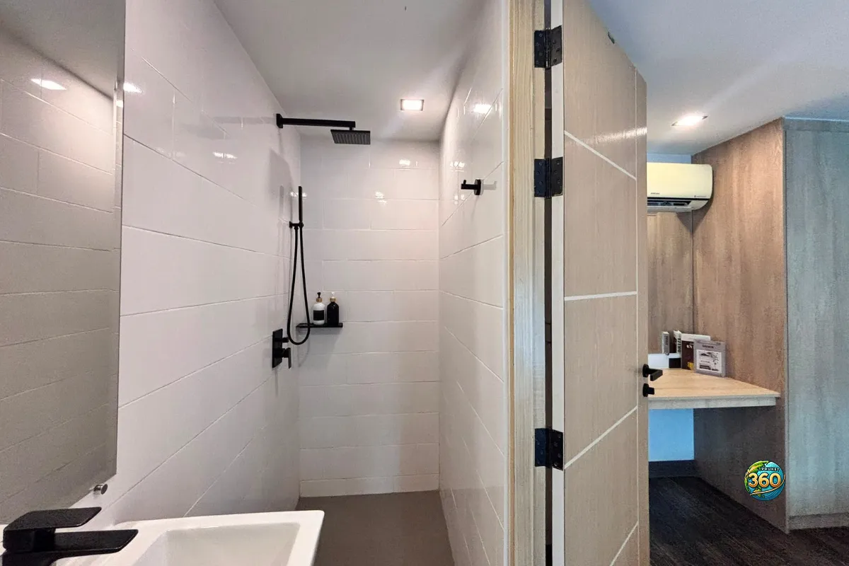 Salle de bain du duplex à Utopia Nai Harn, Phuket, avec douche ouverte, lavabo, robinetterie noire et accès vers la chambre