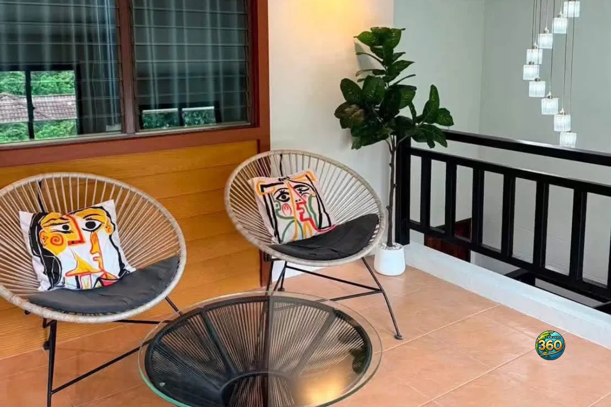 Coin détente à l’étage de la maison 3 chambres à louer à Bang Tao, Phuket, avec deux fauteuils, table ronde, plante décorative et rambarde