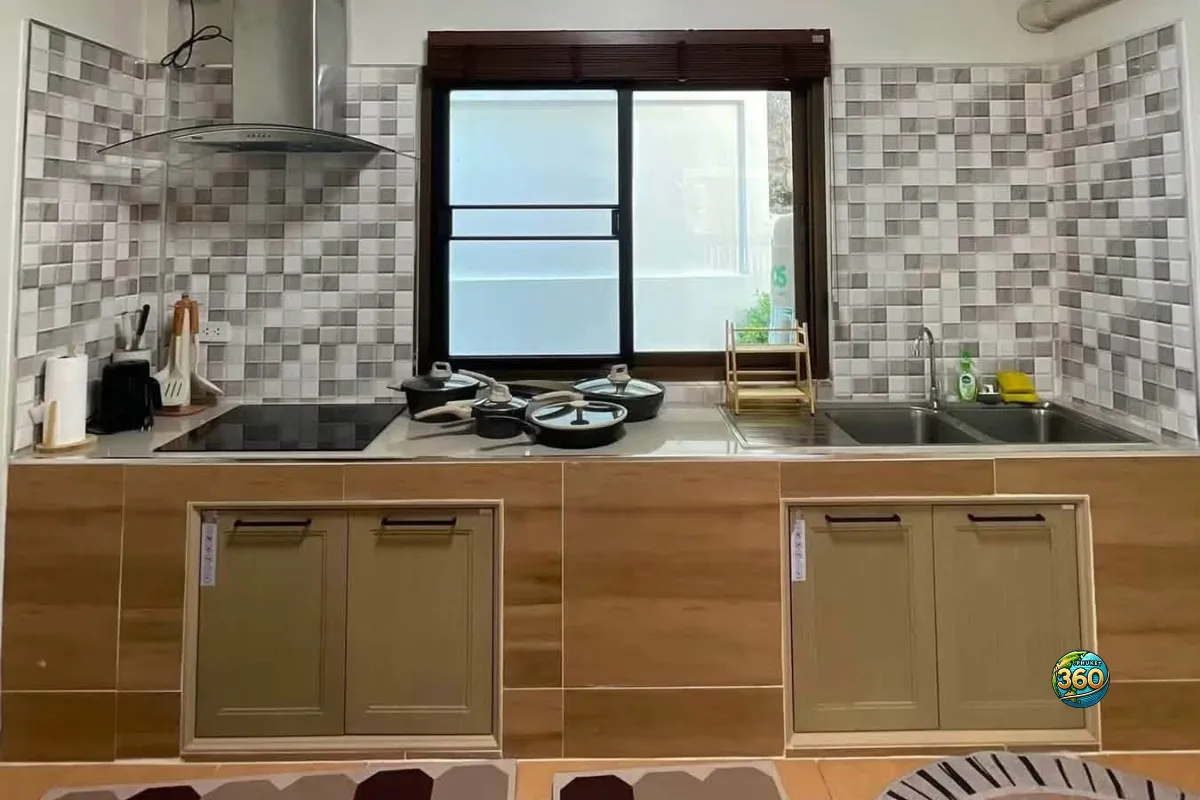 Cuisine de la maison 3 chambres à louer à Bang Tao, Phuket, avec plan de travail, évier, hotte, plaque de cuisson et casseroles
