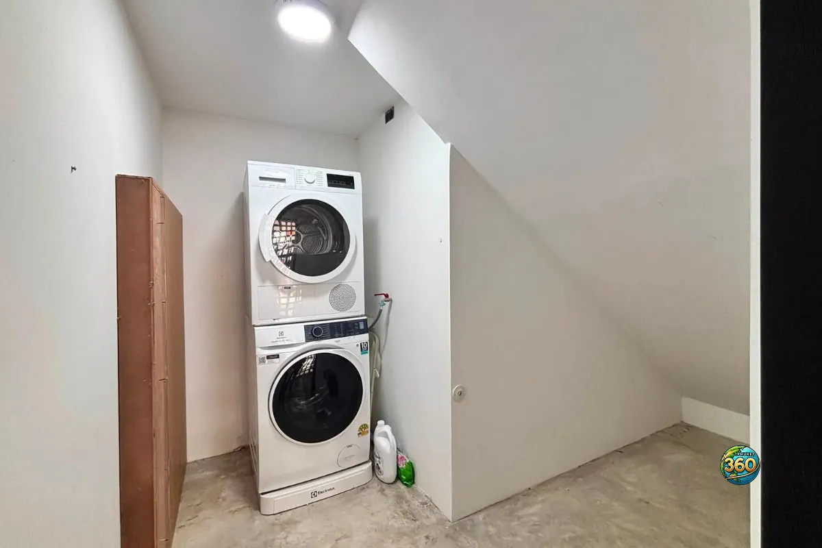 Buanderie de la maison Mono Plus Palai à Phuket avec lave-linge, sèche-linge empilé et espace de rangement sous l’escalier
