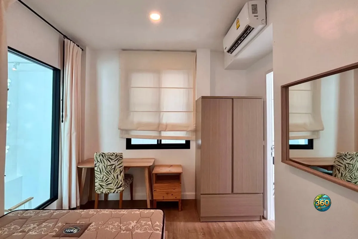 Chambre de la maison Mono Plus Palai à Phuket avec lit, bureau, chaise, armoire, miroir mural et climatisation