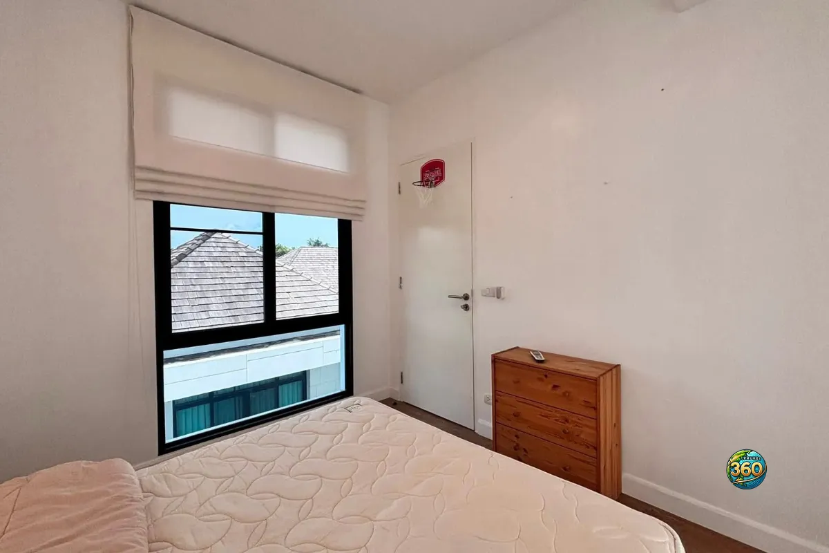 Chambre de la maison Mono Plus Palai à Phuket avec lit double, grande fenêtre, commode en bois et porte intérieure
