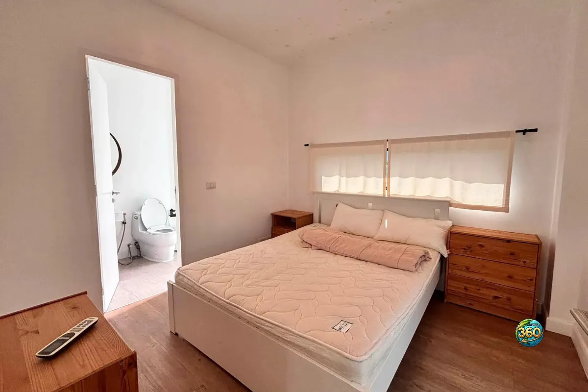 Chambre de la maison Mono Plus Palai à Phuket avec lit double, tables de chevet, commode en bois et salle de bain attenante visible