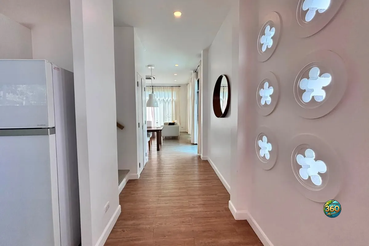 Couloir intérieur de la maison Mono Plus Palai à Phuket avec sol imitation bois, réfrigérateur, mur décoratif et vue vers le salon
