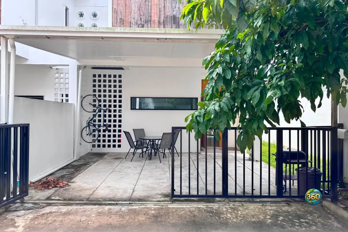 Entrée extérieure de la maison Mono Plus Palai à Phuket avec portail, terrasse couverte, vélo mural et arbre dans la cour