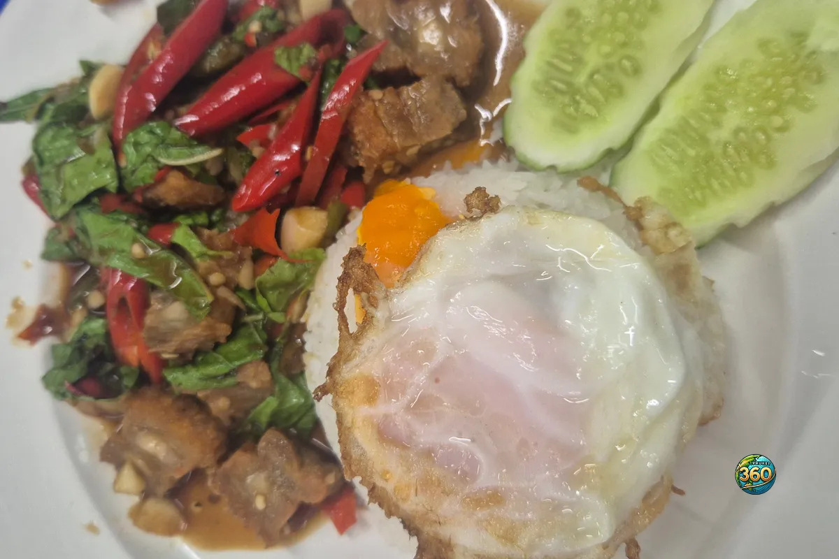 Assiette de pad kra pao au porc croustillant avec riz blanc, œuf frit, piments rouges, basilic thaï et concombre