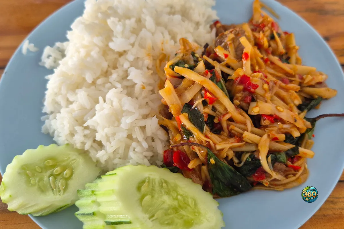 Assiette de pad prik gaeng nor mai avec riz blanc, pousses de bambou sautées au curry rouge, basilic thaï, piments et concombre