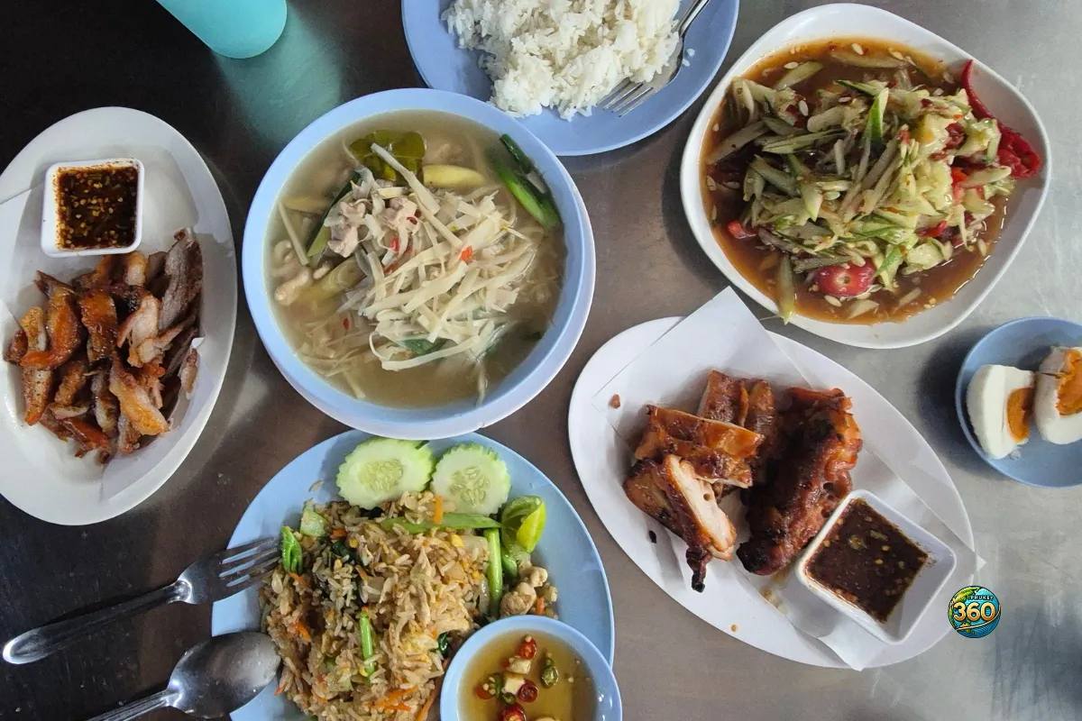 Table de repas thaï avec som tam, riz sauté, poulet grillé, soupe, riz blanc, œufs et sauces pimentées
