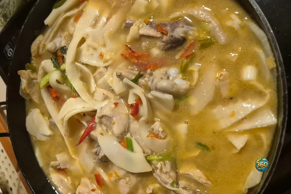 Bol de tom kha gai thaï avec poulet, lait de coco, champignons, piments rouges et herbes fraîches