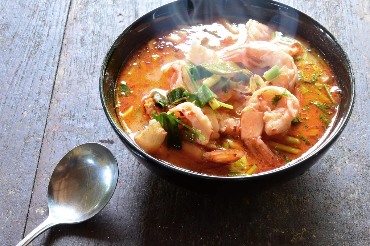 Bol de tom yum goong thaï avec crevettes, bouillon épicé, herbes fraîches